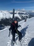 Junge Dame mit Schi auf dem Rücken auf der Schipiste