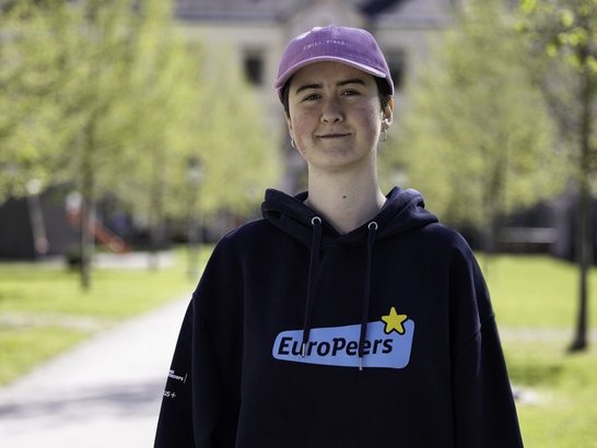 Junge Frau mit rosa Kappe lachelt in die Kamera 