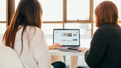 Zwei weibliche Personen sitzen vor Laptop