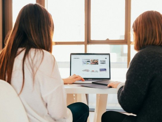 Zwei weibliche Personen sitzen vor Laptop