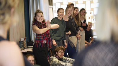 Gruppe junger Menschen steht lachend in einer Linie