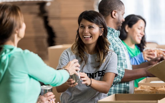 Junge lachende Frau bekommt Lebensmittelspende gereicht 