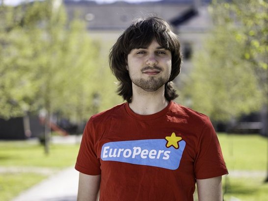 Junger Mann mit dunklen Haare schaut in die Kamera