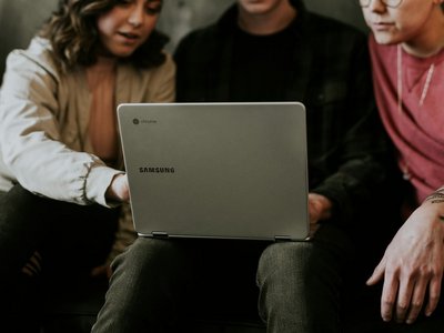 Drei jungen Menschen sitzen vor Laptop