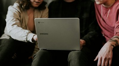 Drei jungen Menschen sitzen vor Laptop