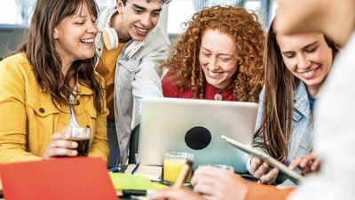 Gruppe junger Erwachsener sitzt gemeinsam vor Laptop 