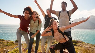 Gruppe lachender junger Menschen im Hintergrund das Meer