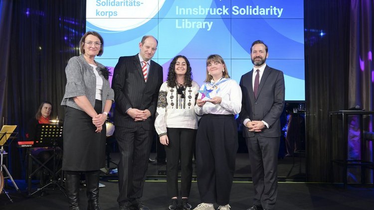 Europa bewegt: Erasmus+ und ESK Award 2024 Gruppenfoto von drei Frauen und zwei Männern auf einer Bühne, dahinter ein Screen mit dem Schriftzug „Innsbruck Solidarity Library“