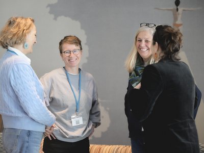 Vier Frauen stehen im Kreis und lachen